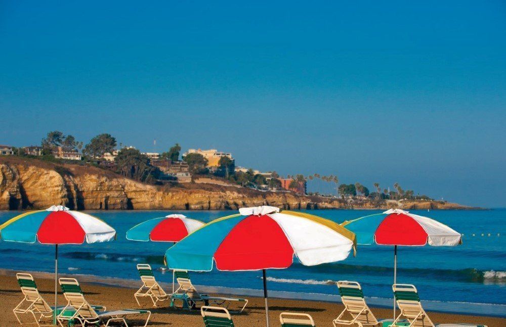 Beach chairs set up under colorful umbrellas on the private beach.