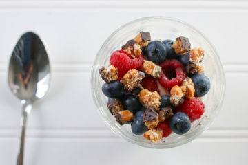 A finished Greek yogurt parfait with fresh fruit and goodnessknows squares.