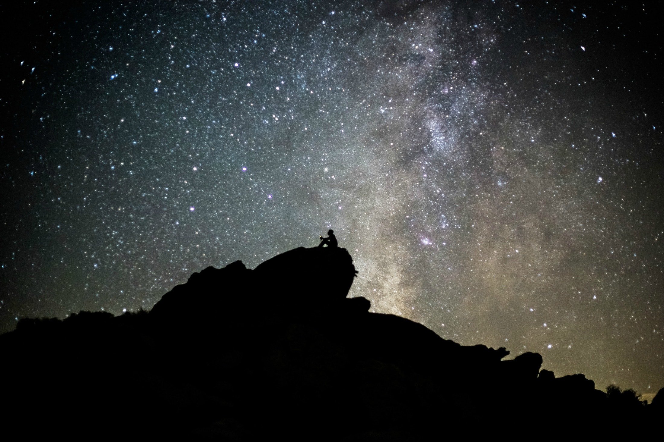 A man sits on a rock under stars — stargazing is one of the very popular things to do at Anza-Borrego Desert State Park