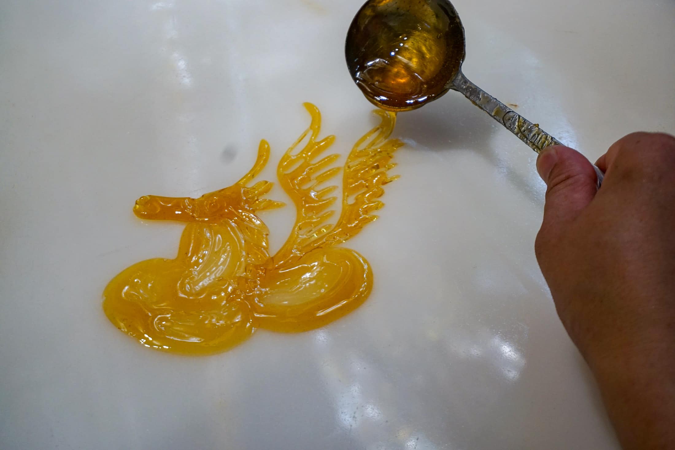 The man pours sugar onto a slab to create the sugar art.