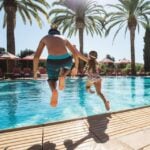 A father and daughter jump into the Main Pool at Fairmont Grand Del Mar.