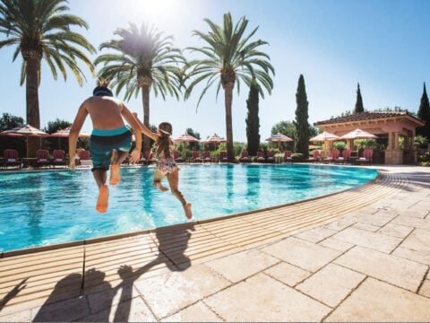 A father and daughter jump into the Main Pool at Fairmont Grand Del Mar.