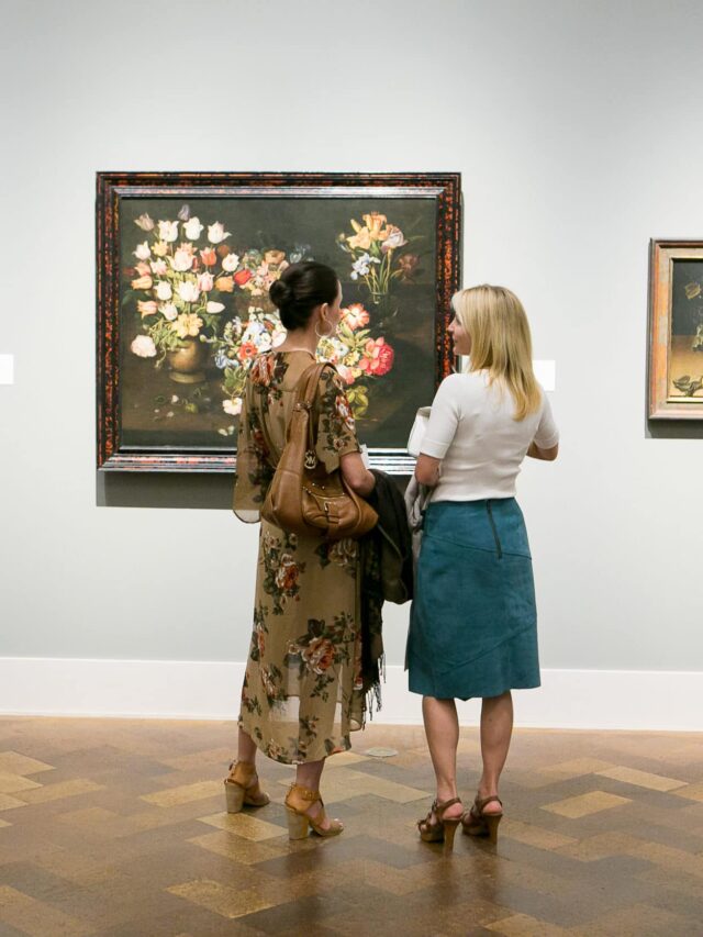 Two women stand in front of a painting at San Diego Museum of Art
