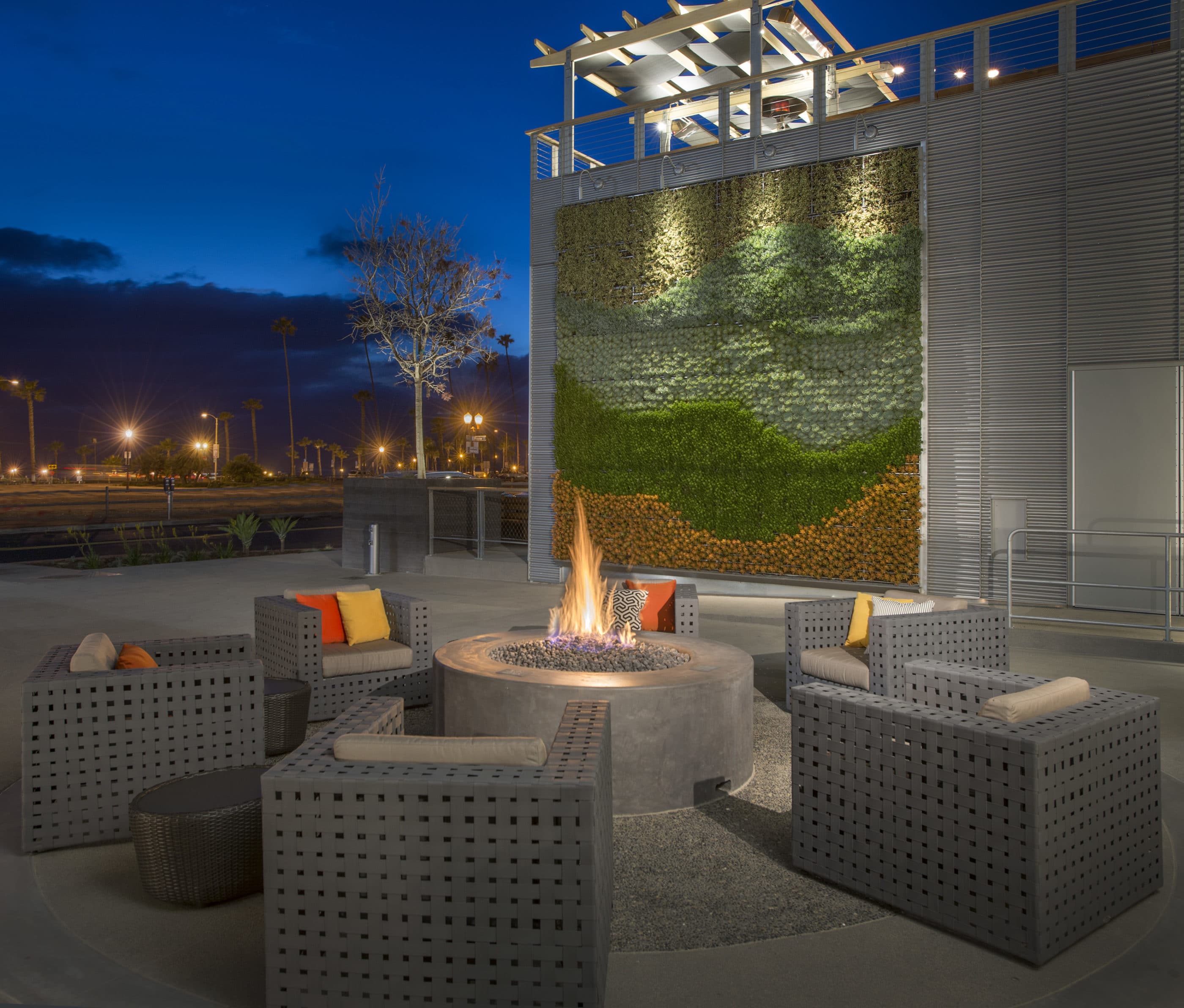 Outdoor fire pit lit up at night and surrounded by lounge chairs
