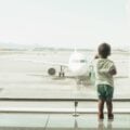 Boy at the airport looking at an airplane at the gate.