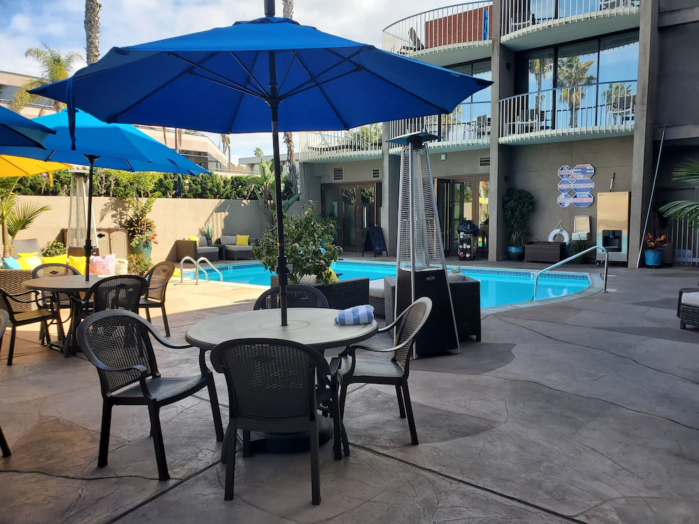 The pool surrounded by tables and simple lounge seating at Inn by the Sea La Jolla.