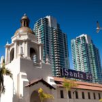 Exterior shot of Santa Fe Depot's Mission Revival style bell tower and exterior set against modern buildings.
