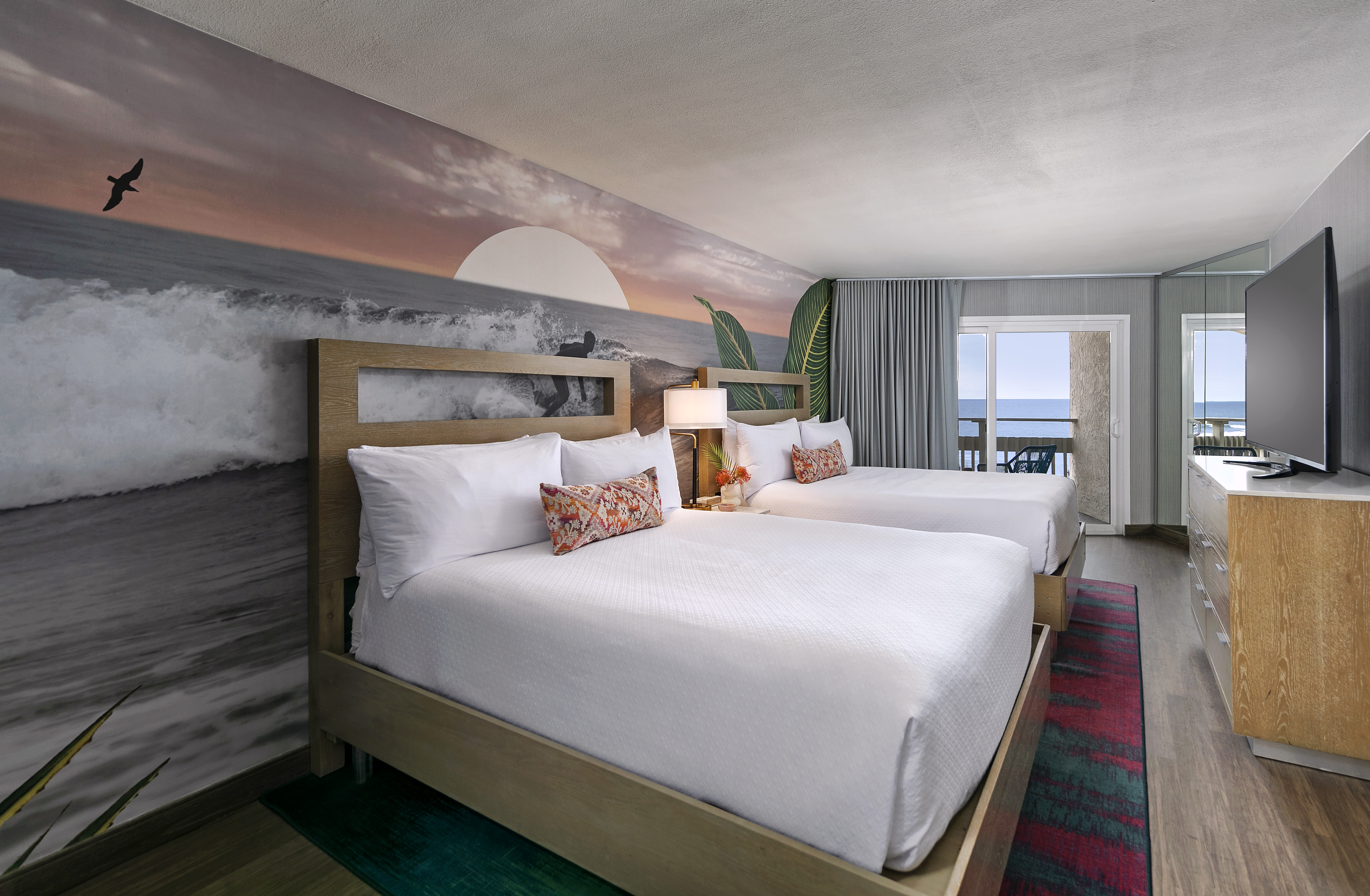 Two queen bed room interior with a sunset mural.