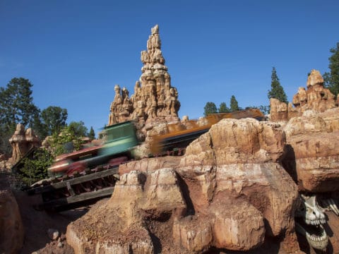 A Big Thunder Mountain Railroad train speeds past the red mountain.