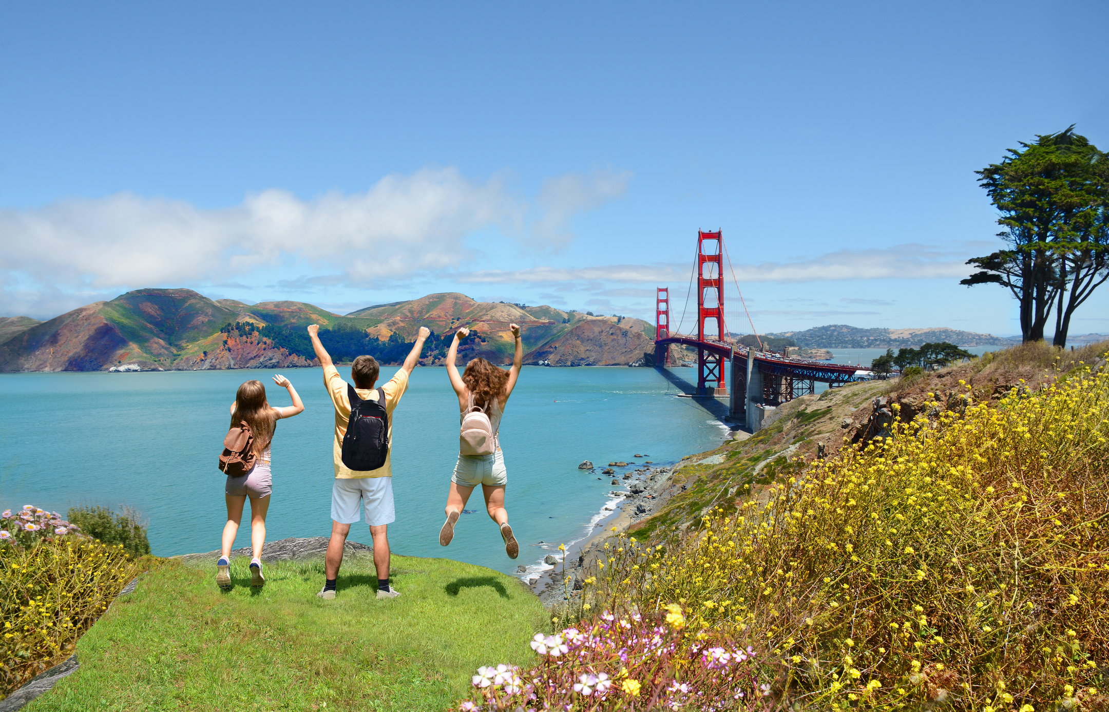A family jumps in the air near the Golden Gate Bridge.