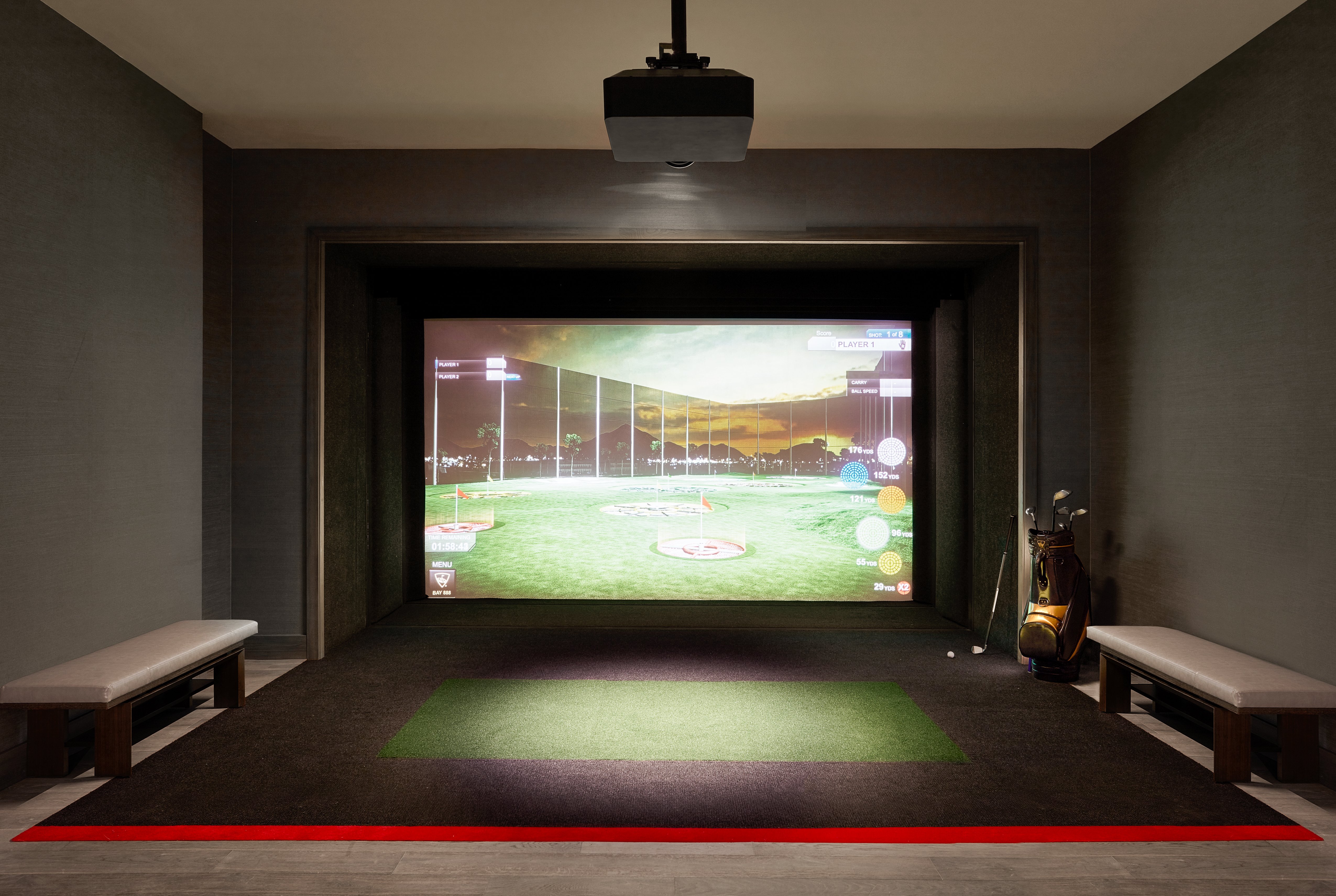 The giant screen, seating, and golf clubs in the TopGolf Suite.