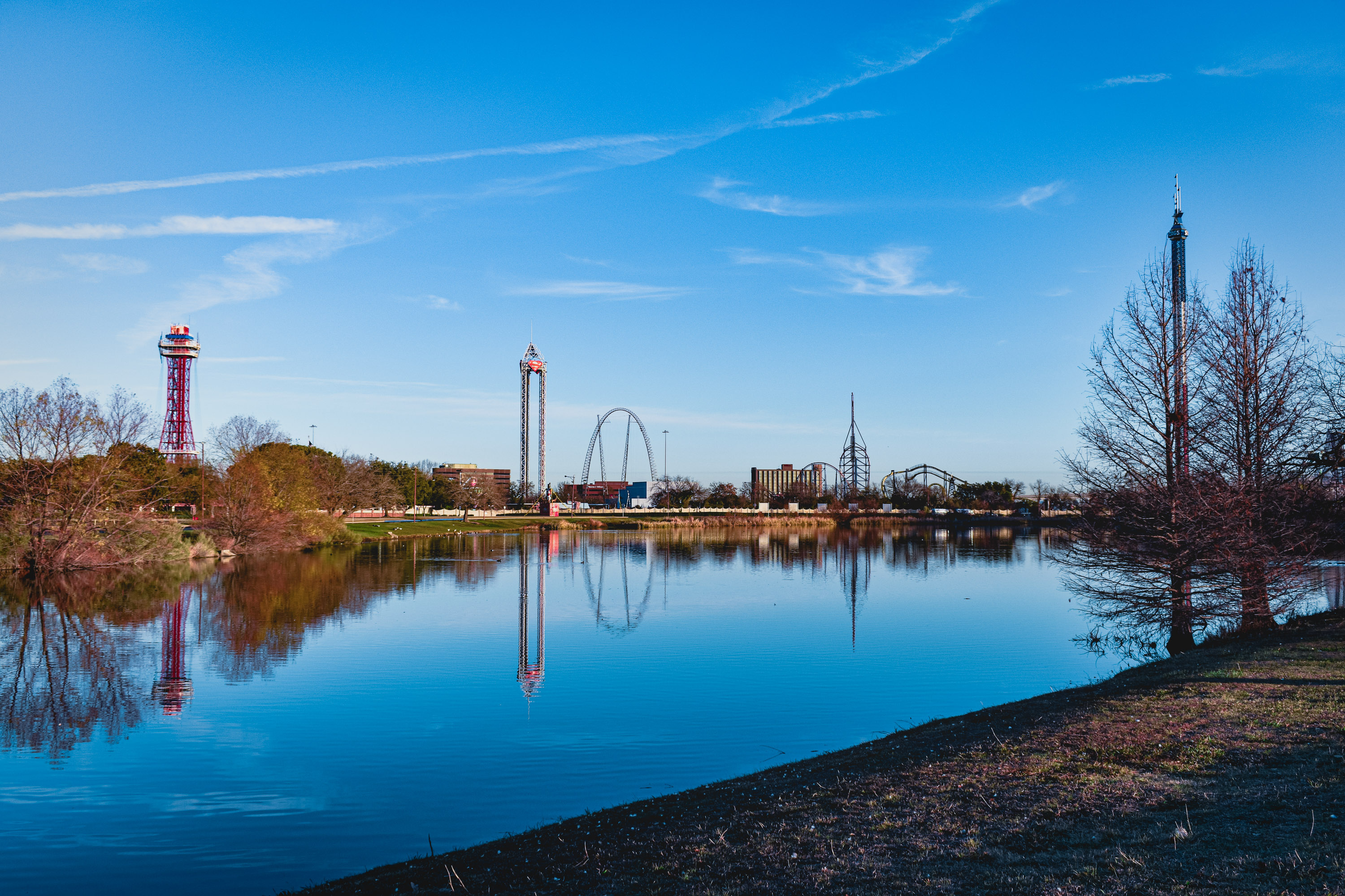 Six Flags Over Texas reflecting off of a lake.