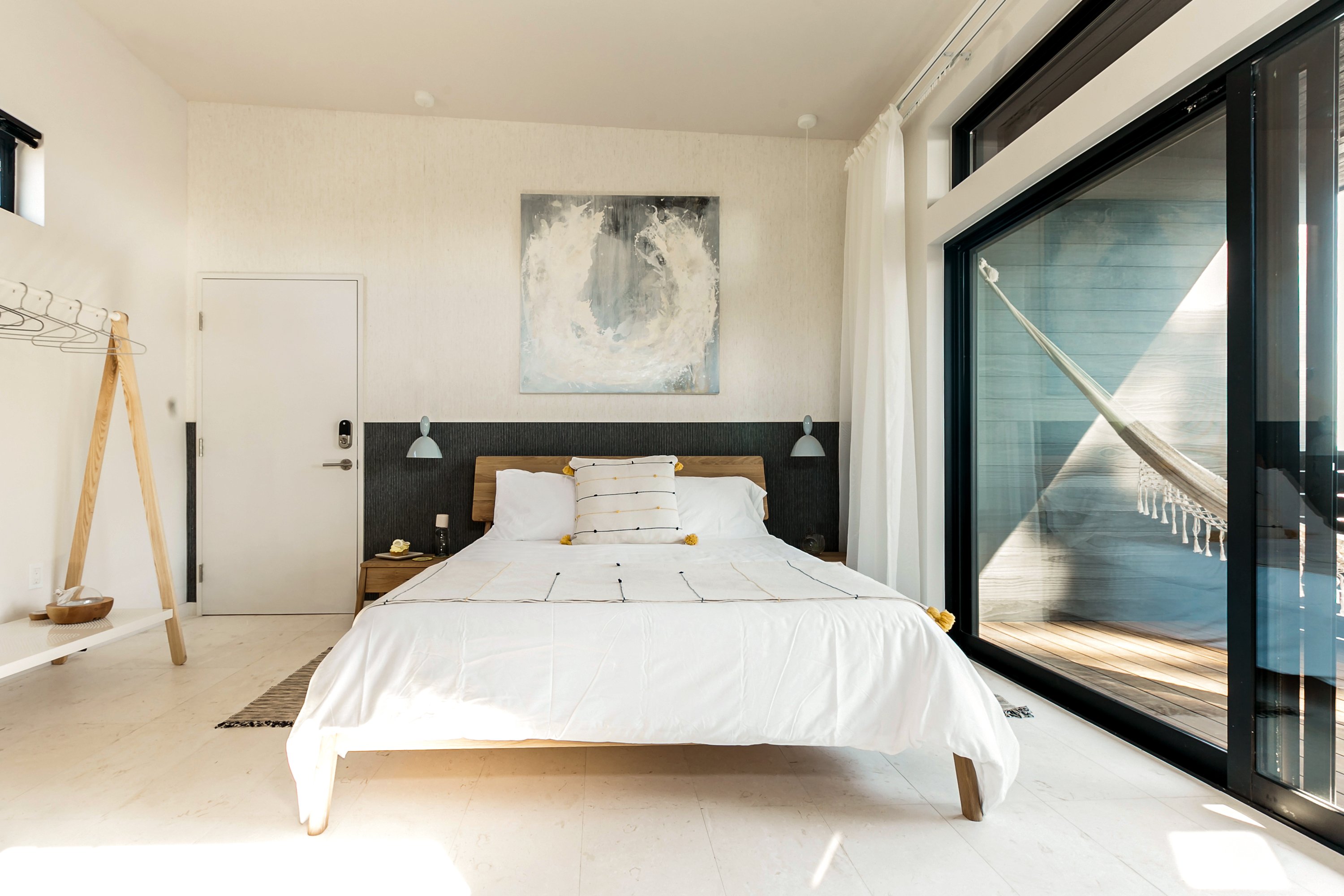 A king bedroom interior with view of hammock on the balcony.