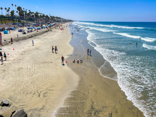 View from the pier of people walking on the sand in Oceanside.