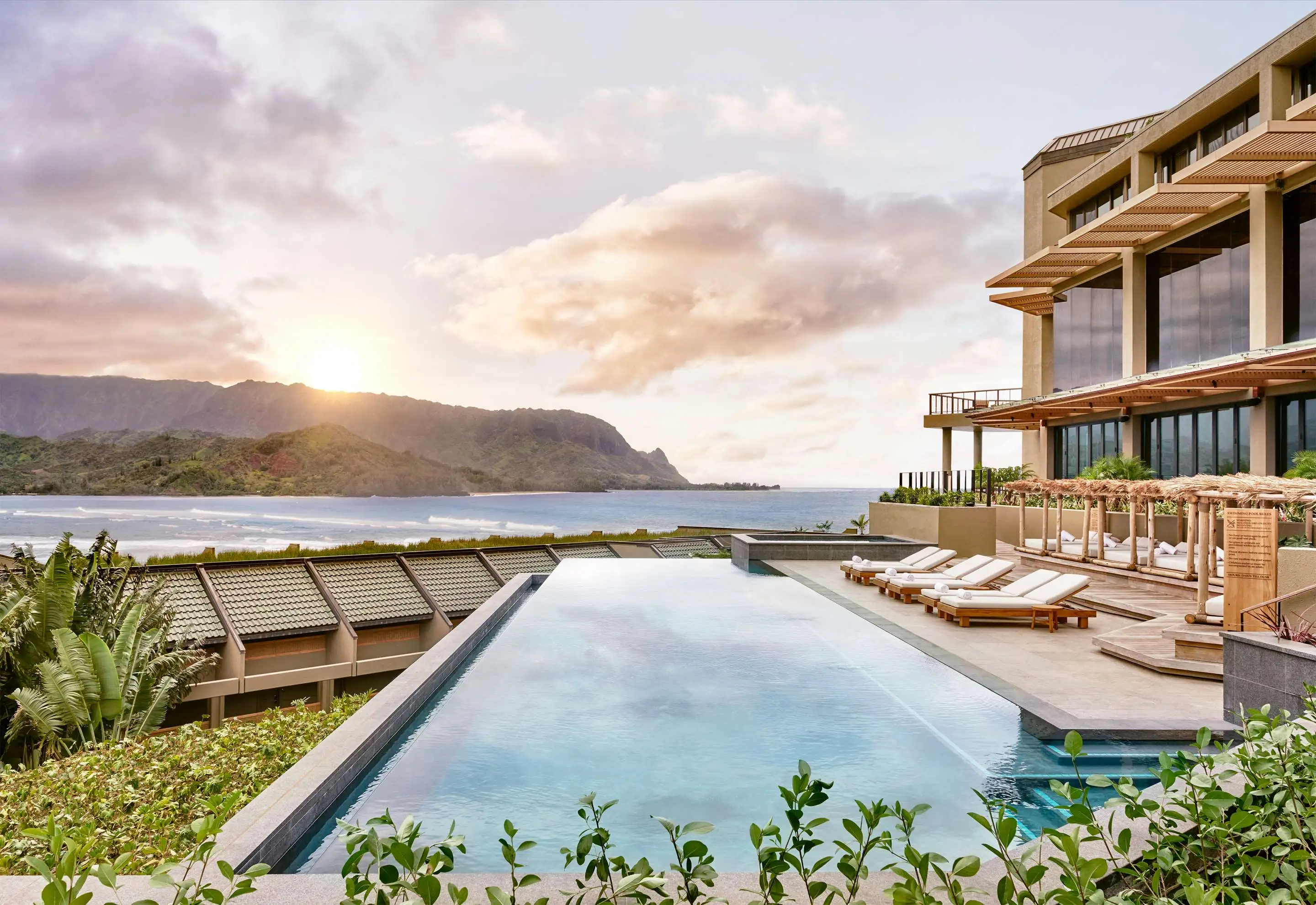 Swimming pool with lounge chairs adjacent to the ocean at 1 Hanale Bay.