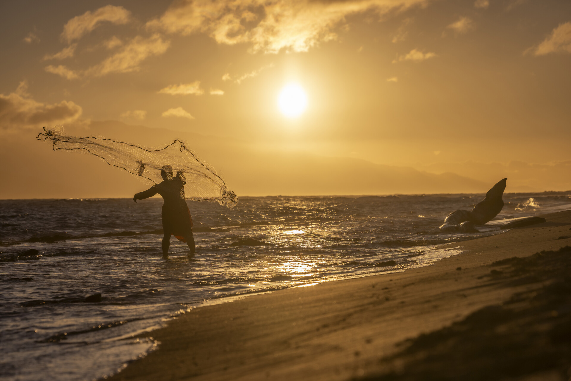 a man fishing during sunset in the beach