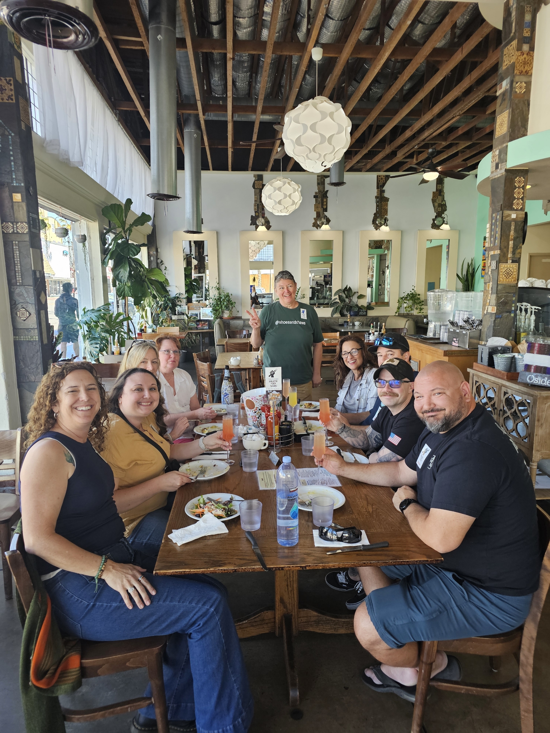 A tour group at a table with champagne drinks and food.