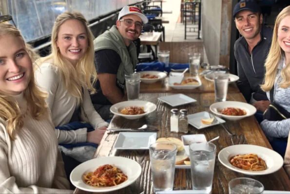 A tour group at a table enjoying pasta.