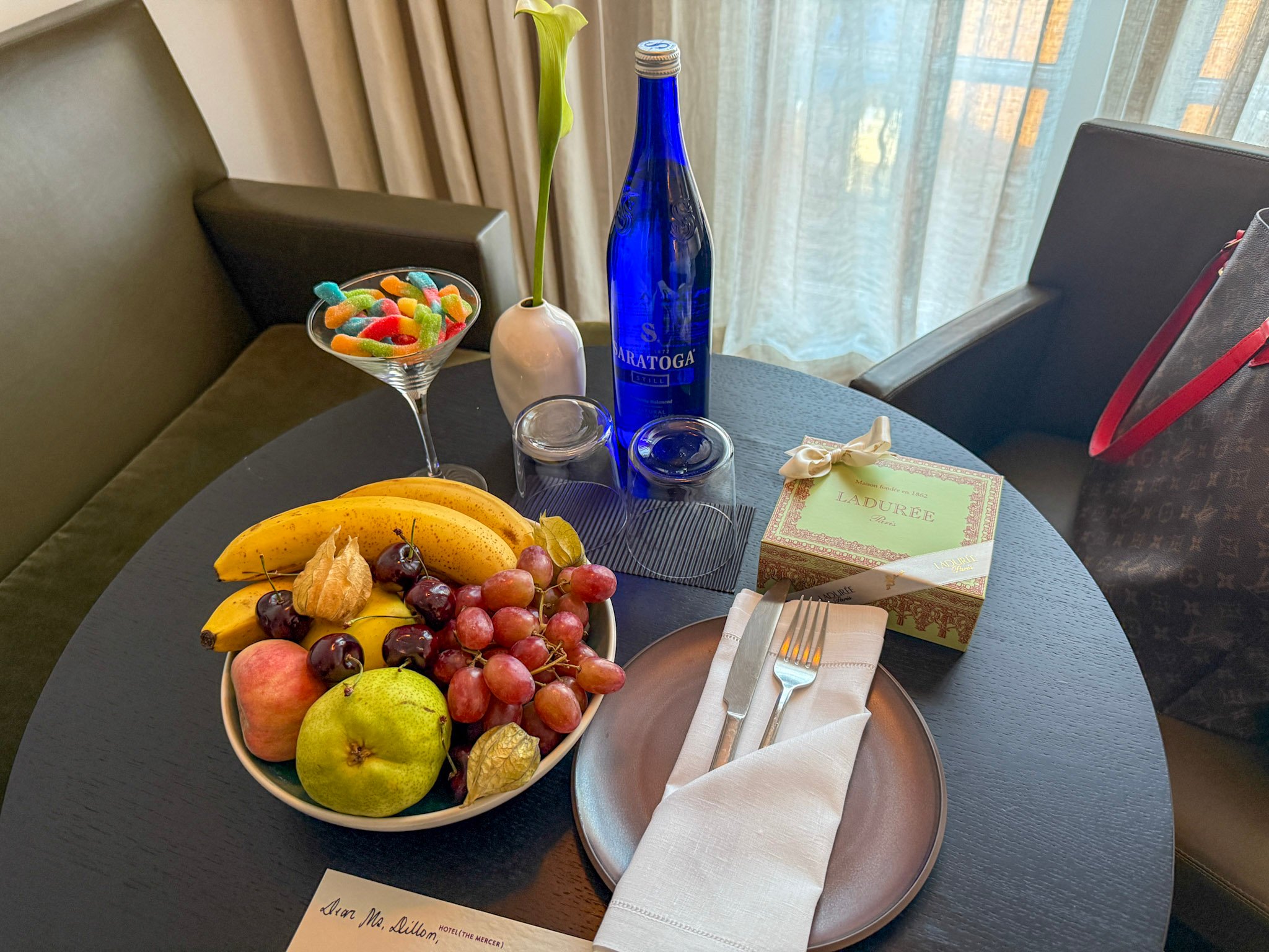 A fruit bowl, bottled water, Laduree cookie, and gummy worms welcome amenity.