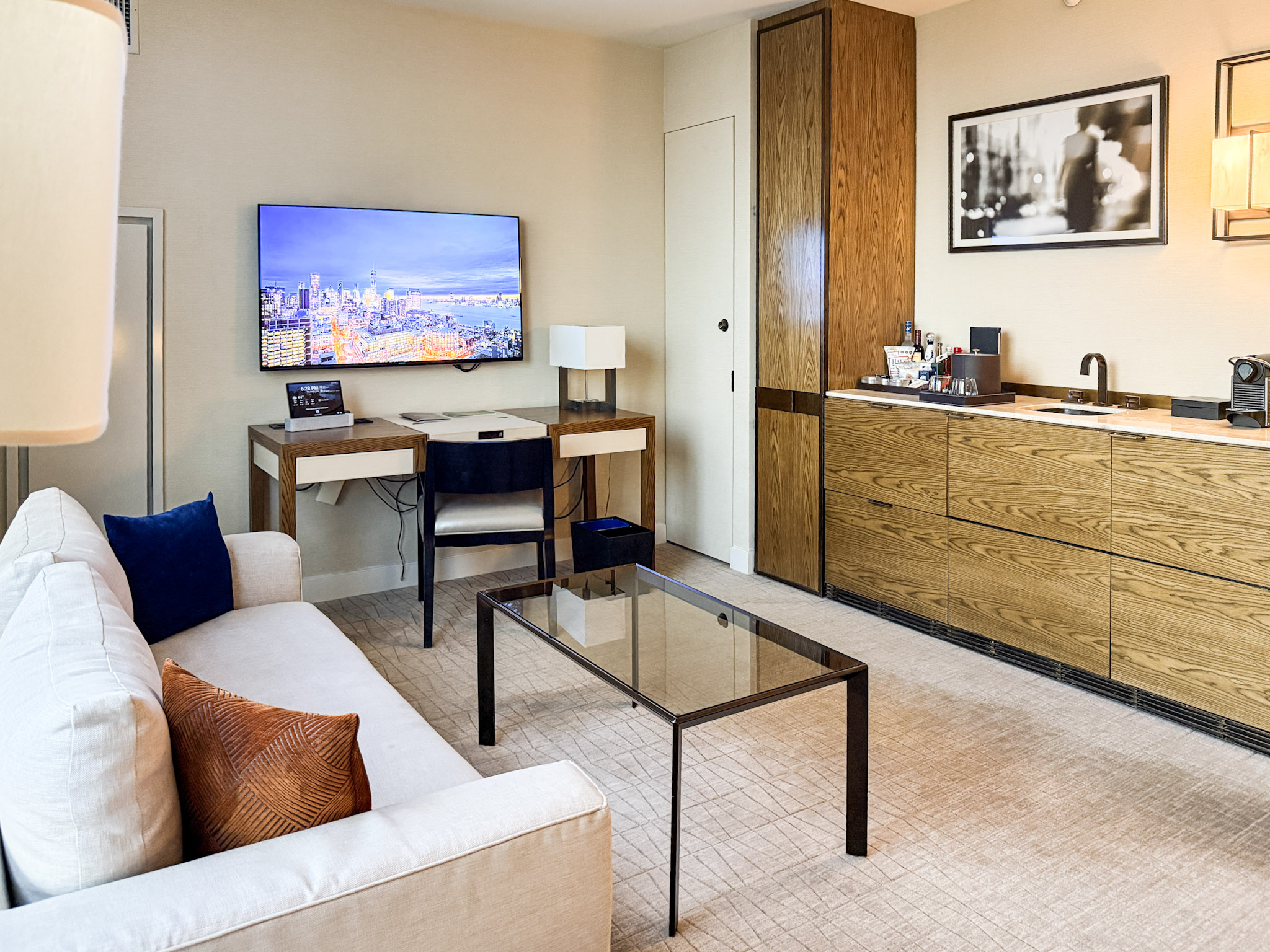 Living area with sofa, desk and wet bar.
