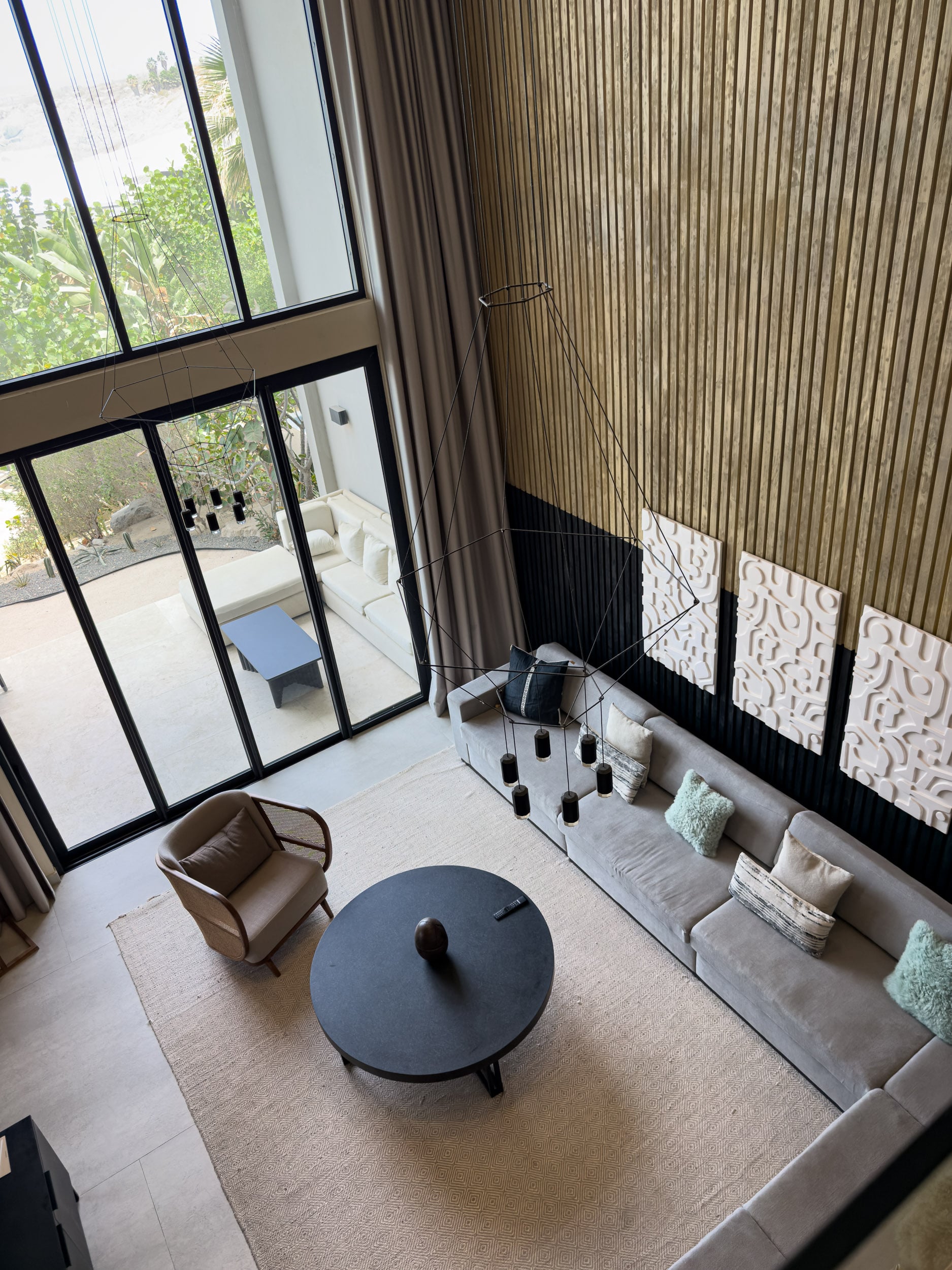 The double-height living area of a residence at The Cape, with floor-to-ceiling windows and a sectional sofa