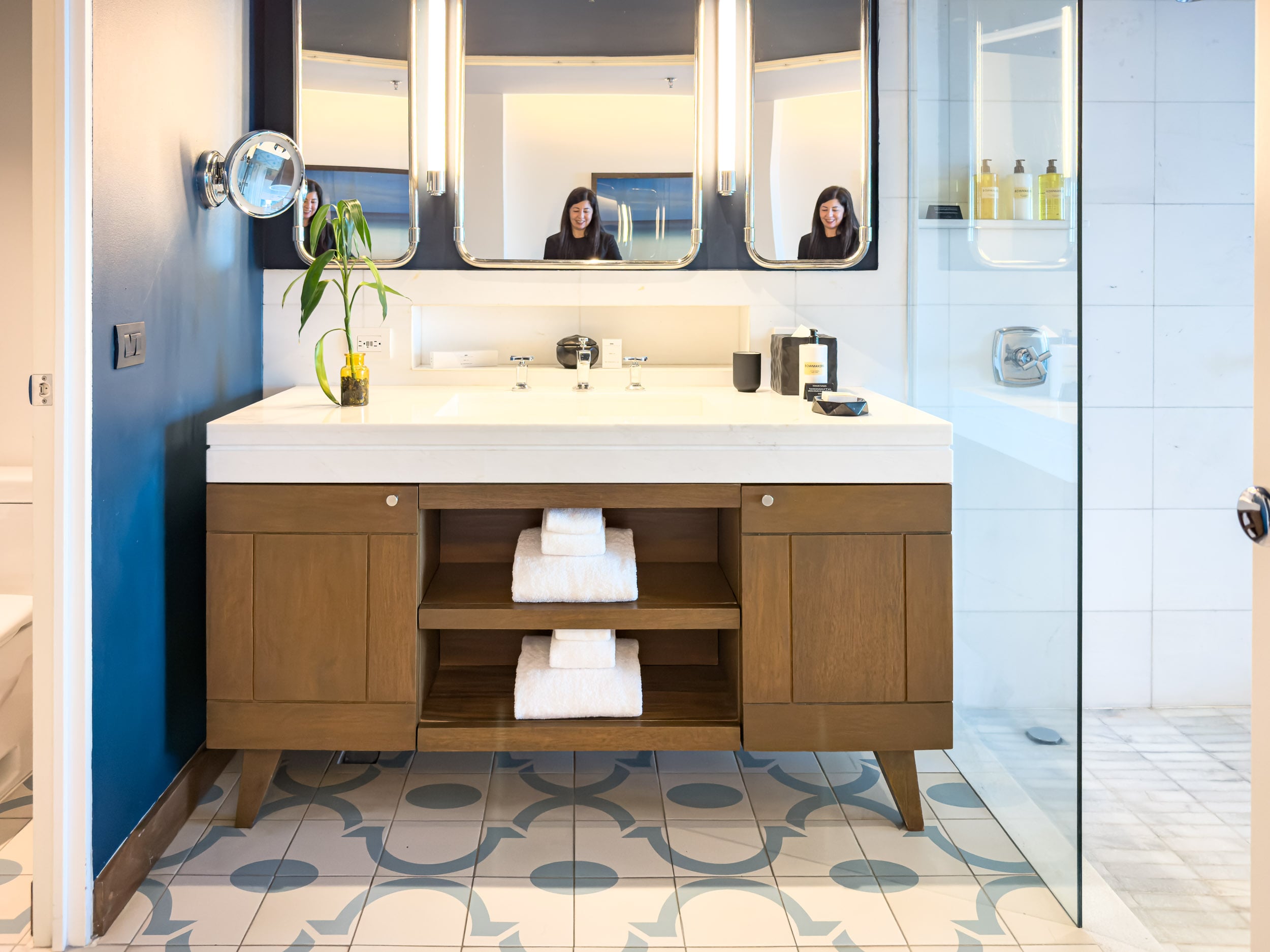 Double vanity with lighted mirrors and wood cabinet in a guest bathroom at The Cape, a Thompson Hotel