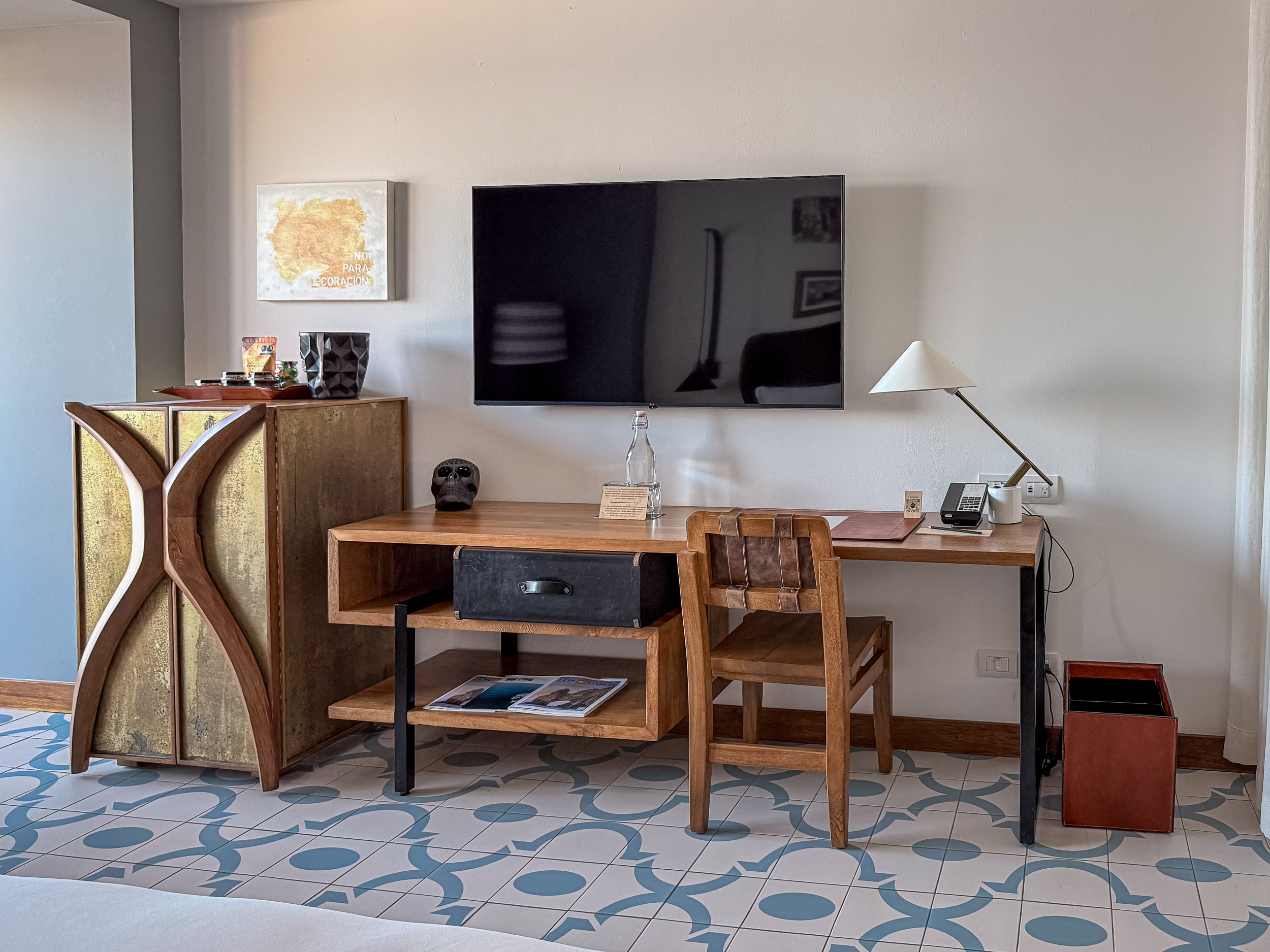 Guest room desk and media console with patterned tile floor at The Cape, a Thompson Hotel