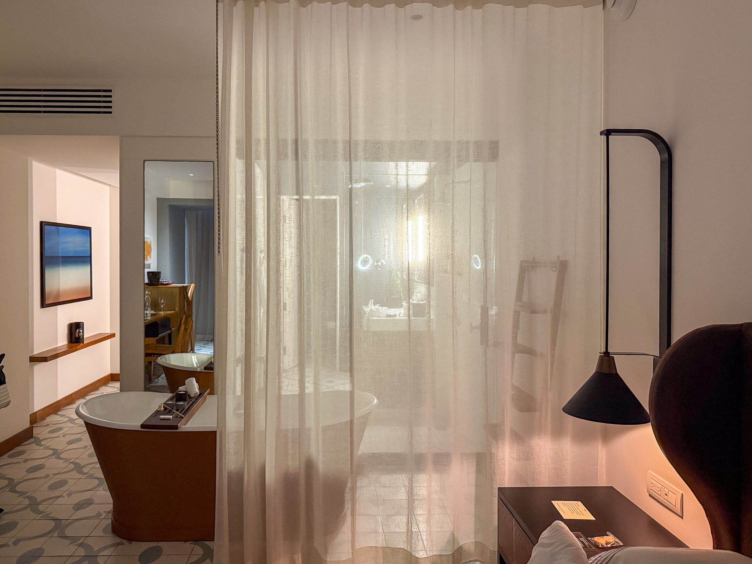 Living area with sheer curtains in a suite at The Cape, a Thompson Hotel