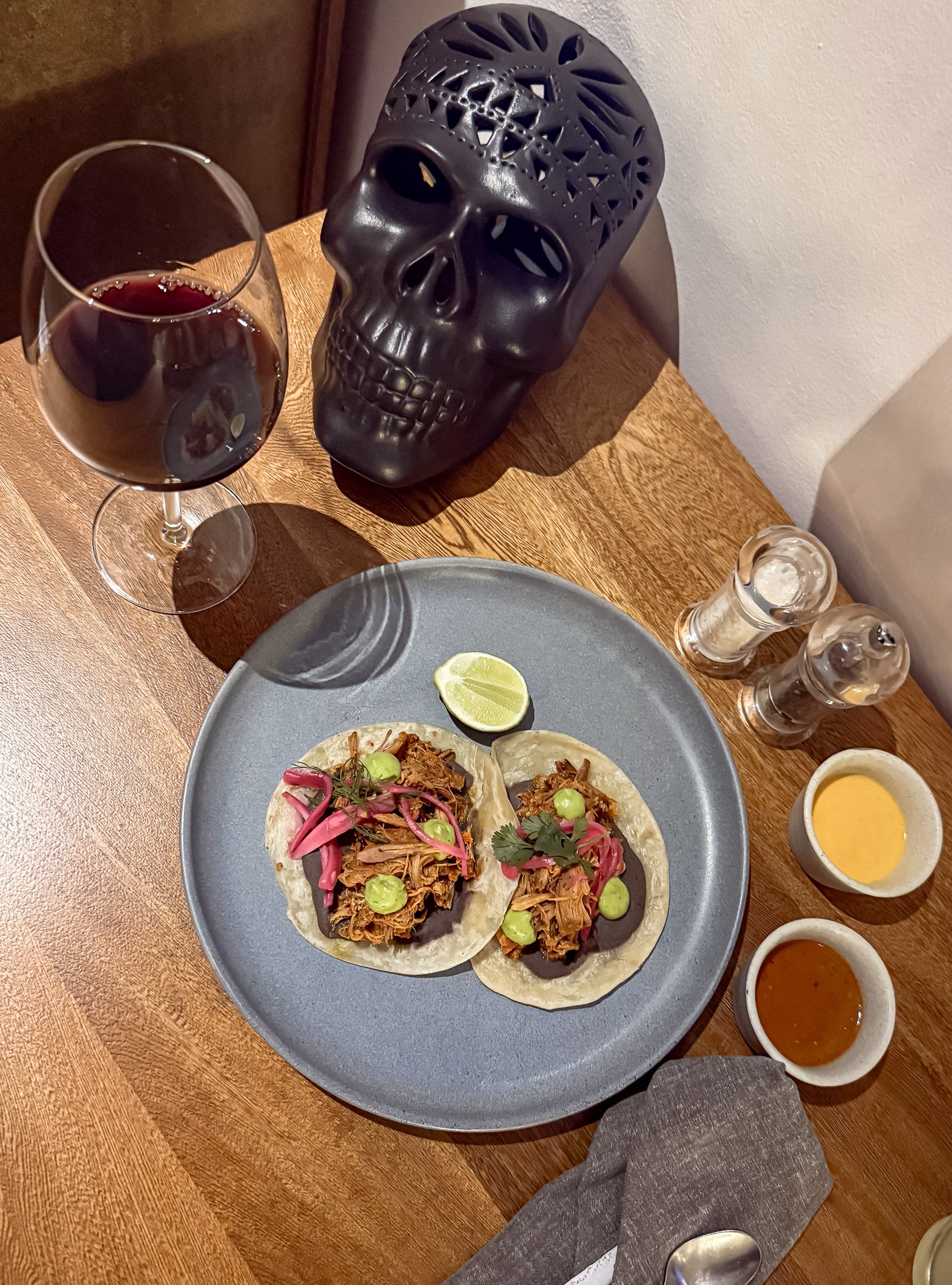 Tacos and a glass of red wine on a wood table at The Cape, a Thompson Hotel