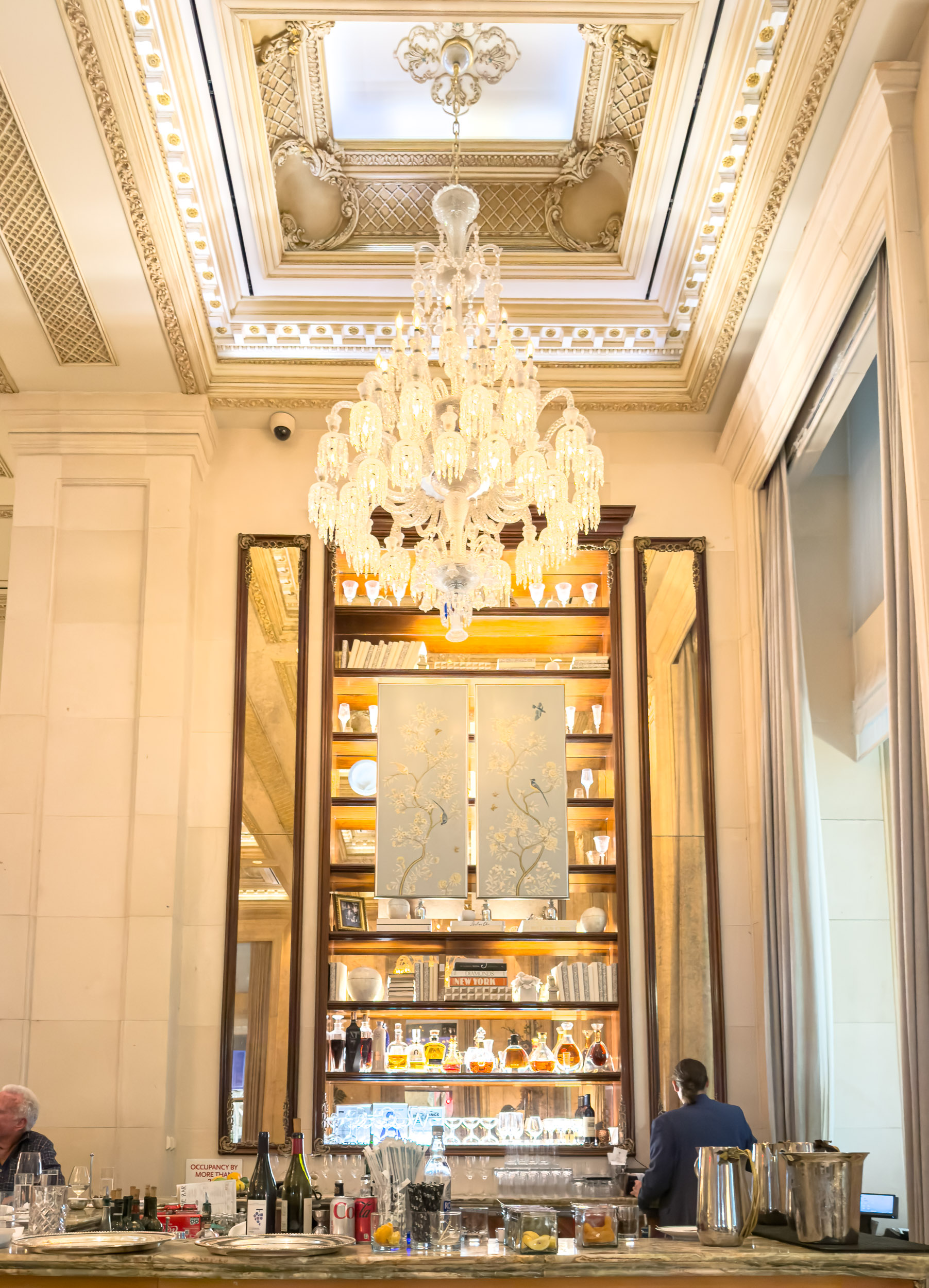 Champagne bar with crystal chandelier and floor-to-ceiling shelving at The Plaza Hotel New York