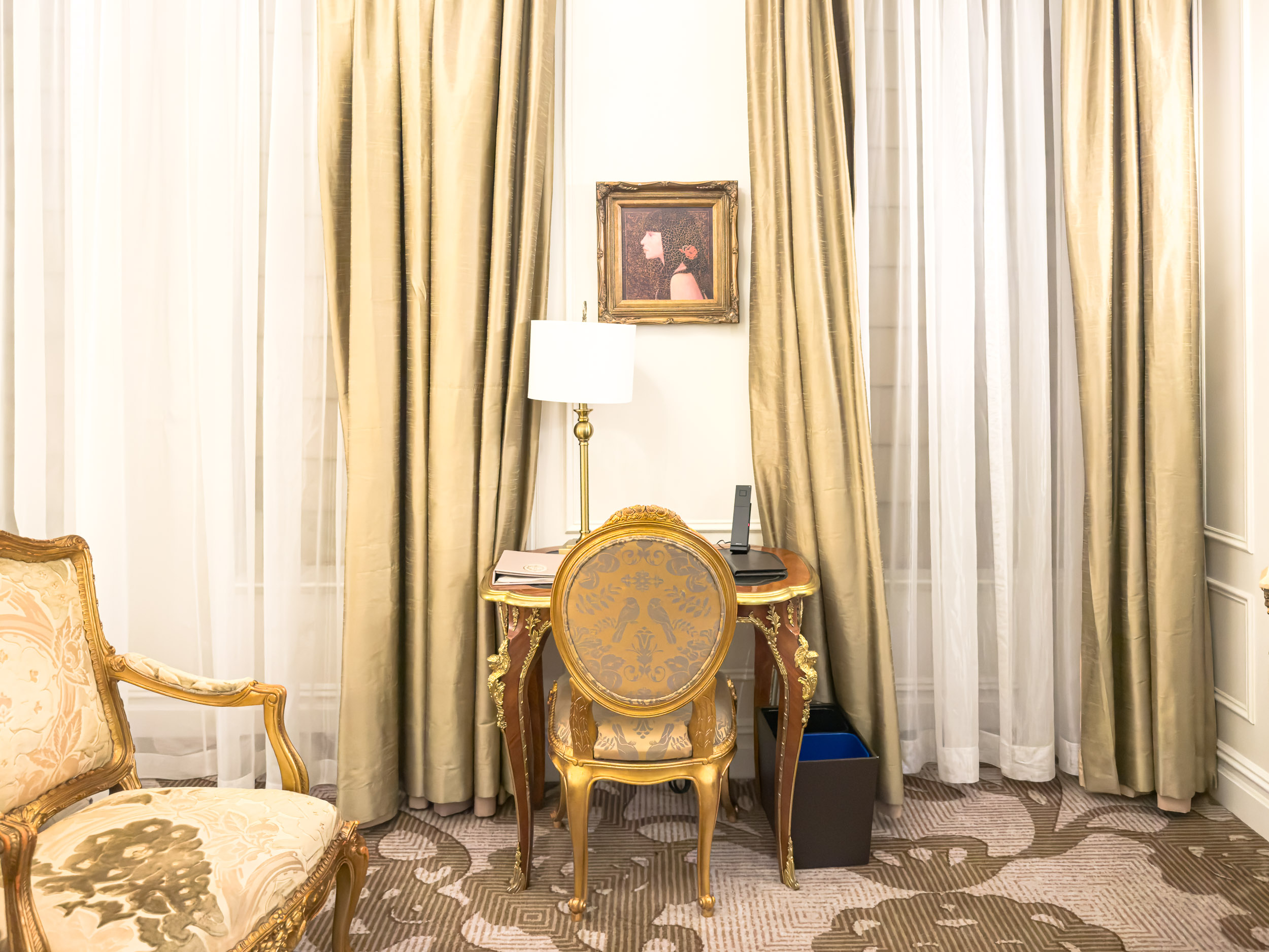 Sitting area with writing desk and silk curtains in a guest room at The Plaza Hotel New York