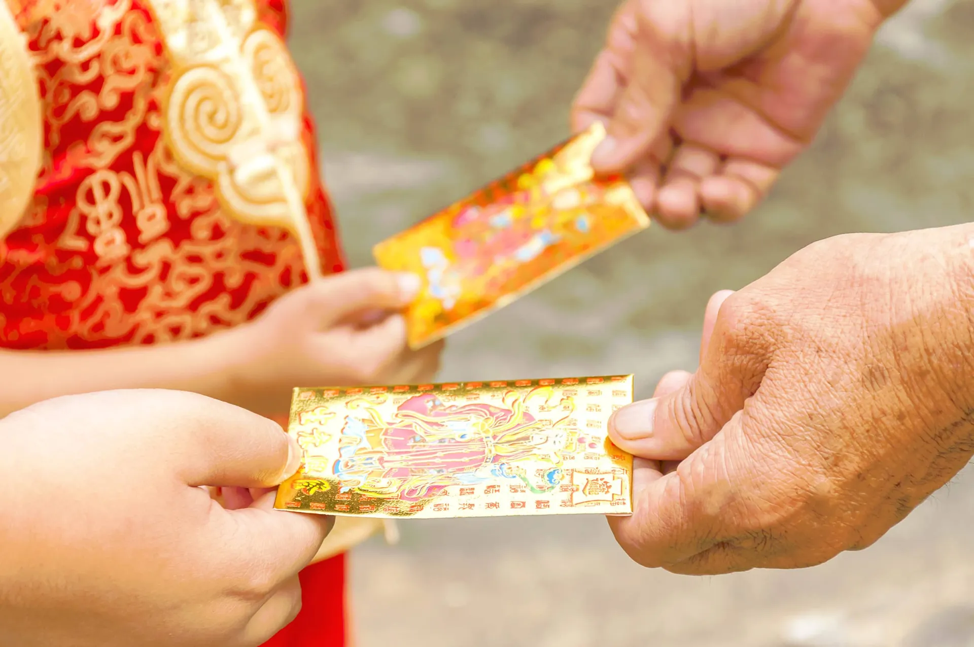 An elder gifts Chinese New Year red envelopes to a child.