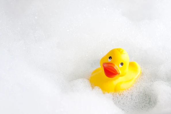 A rubber duck floats in a bathtub full of bubbles..