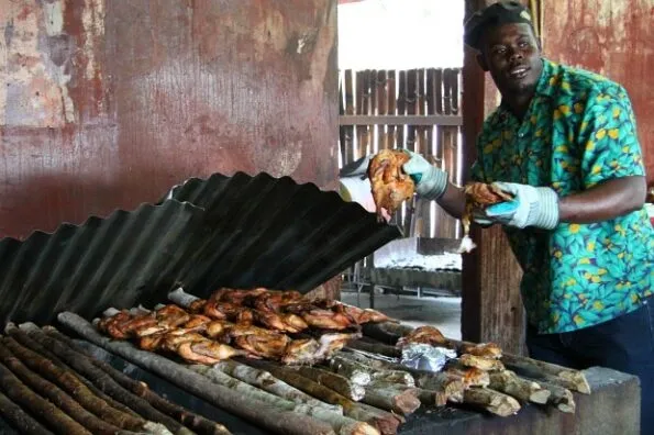 A Scotchies staff member lifts up the metal cover to showcase chicken cooking on the pimento branches.
