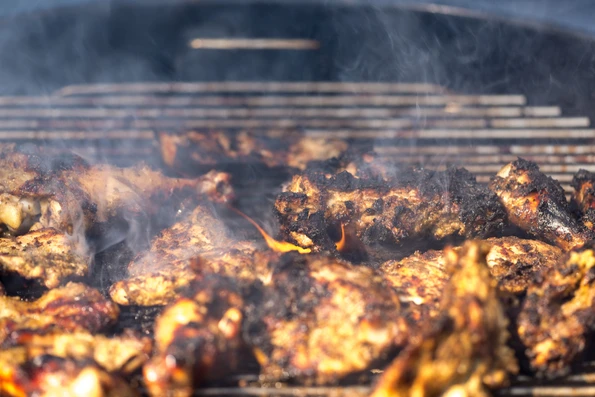 Grilling traditional Jamaican spicy jerk chicken with over wood fire.