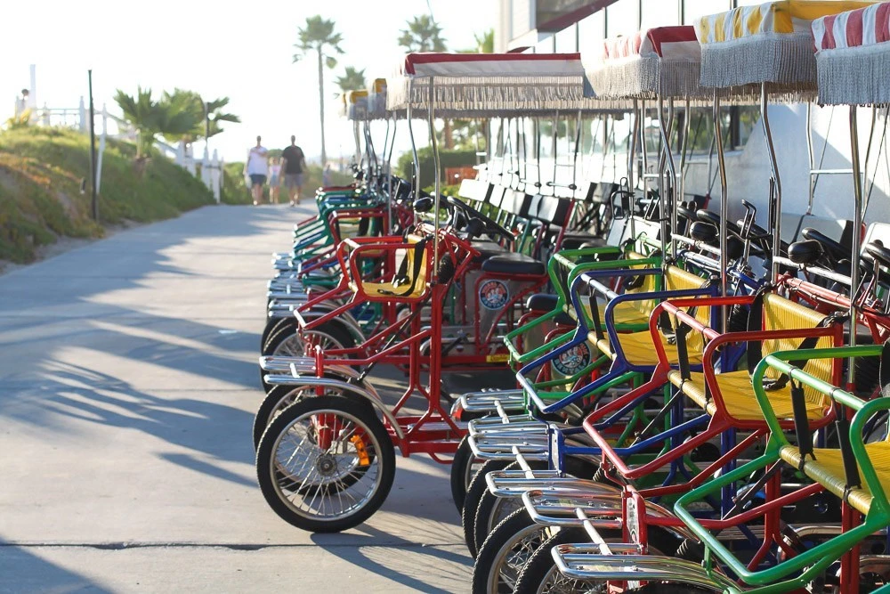 Hotel Del Coronado bike rentals with surreys lined up near the boardwalk.