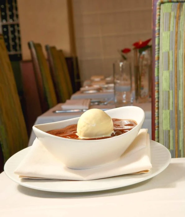 NINE-TEN's half-baked chocolate cake with ice cream on top served on a table inside of the restaurant.