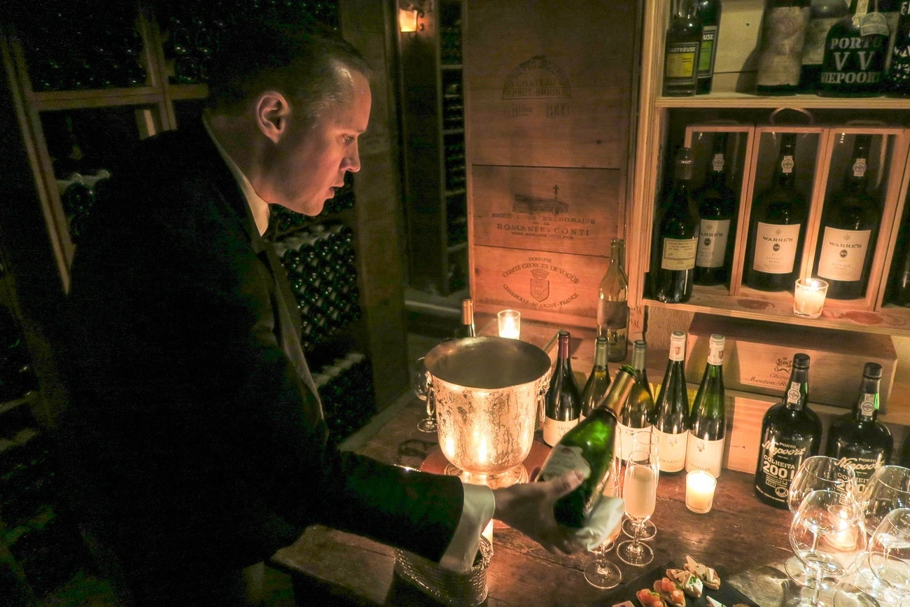 A sommelier pours wine for hotel guests in the famous Le Cinq wine cellarl