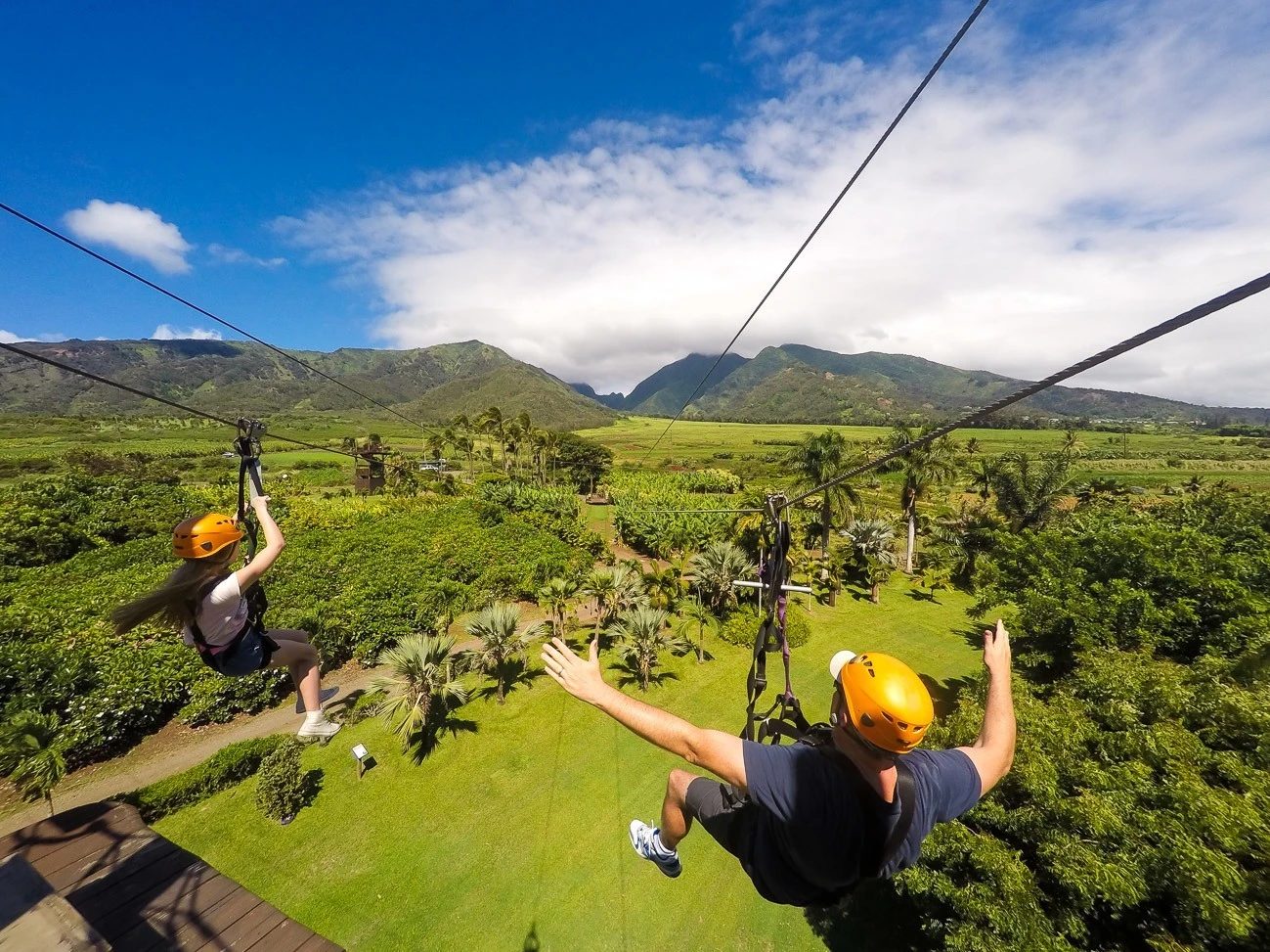 My daughter and husband zip line over a lush plantation with panoramic views at Maui Zipline.