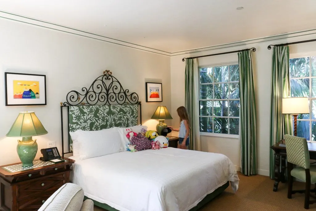 My daughter places stuffed animals on the white bed.