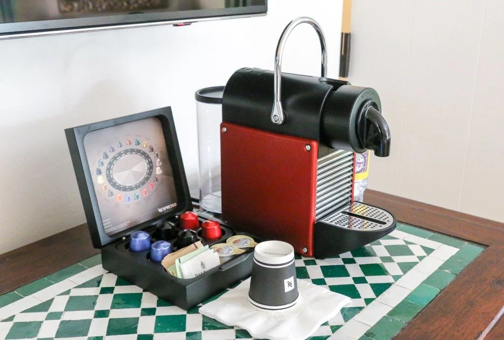 Nespresso coffeemaker and pods on green tiled table