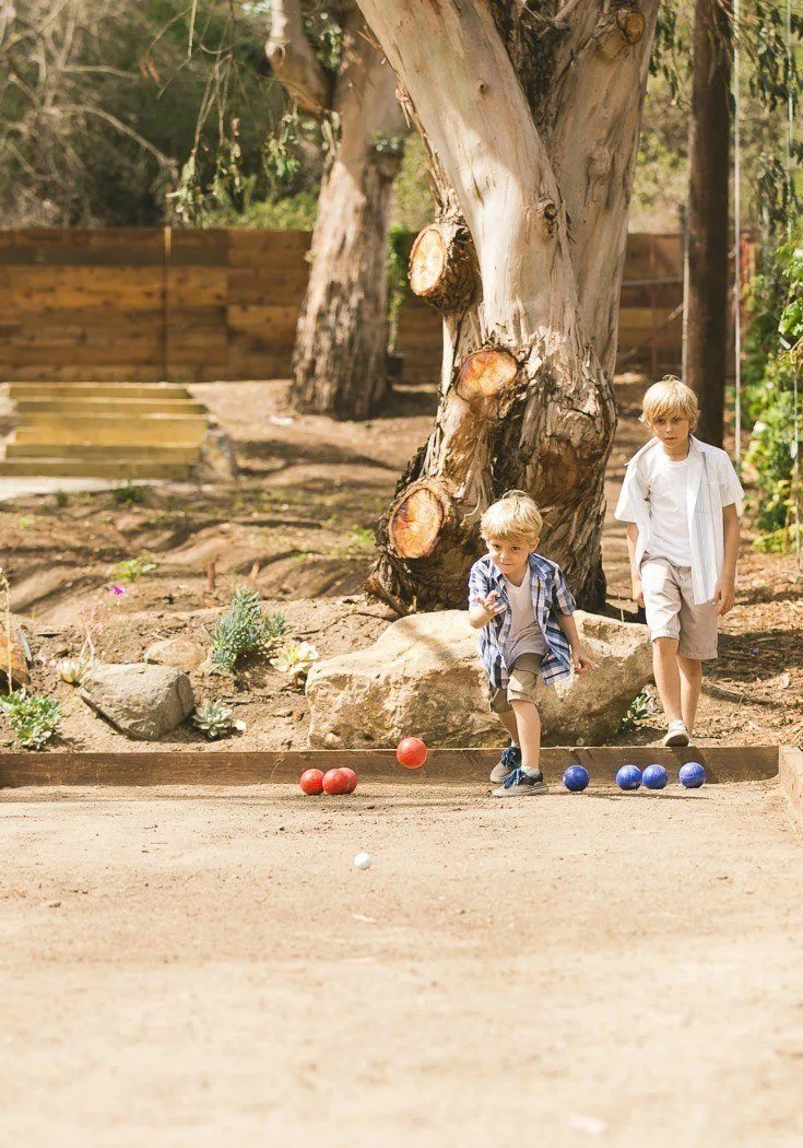 Kids play bocce ball outside.