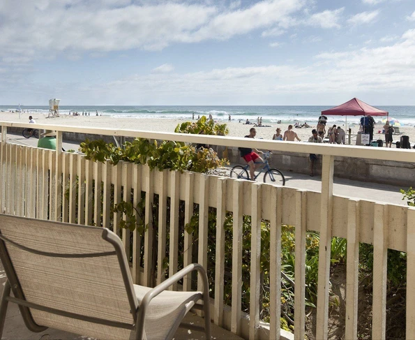 A chair on the patio overlooks Ocean Front Walk boardwalk and beachgoers at Pacific Beach.