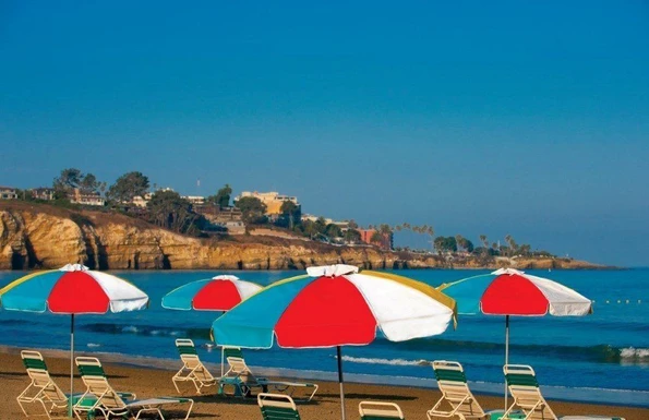 Beach chairs set up under colorful umbrellas on the private beach.