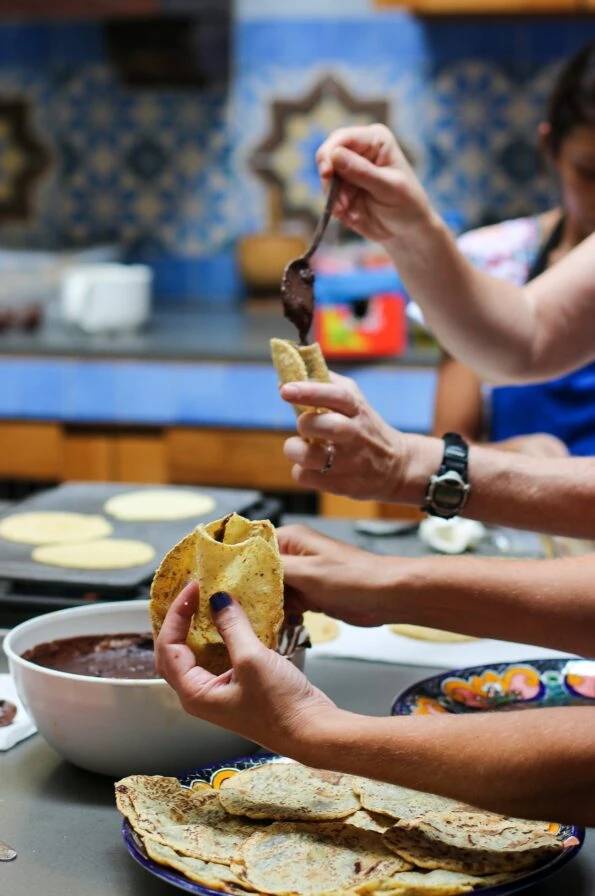 Housemade tortillas being stuffed with black beans for panuchos
