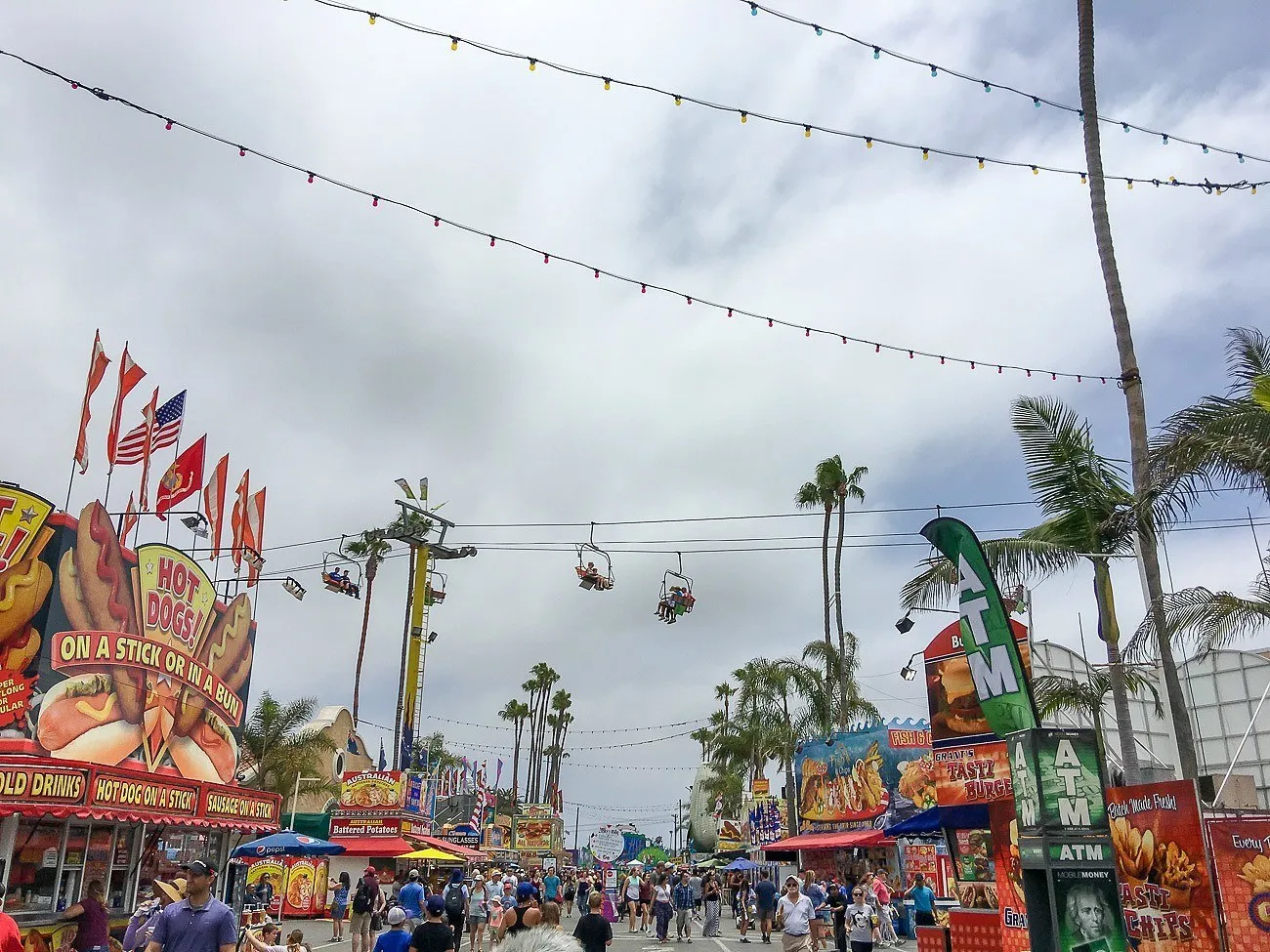 People walking around San Diego County Fair in shorts on a cloudy day.