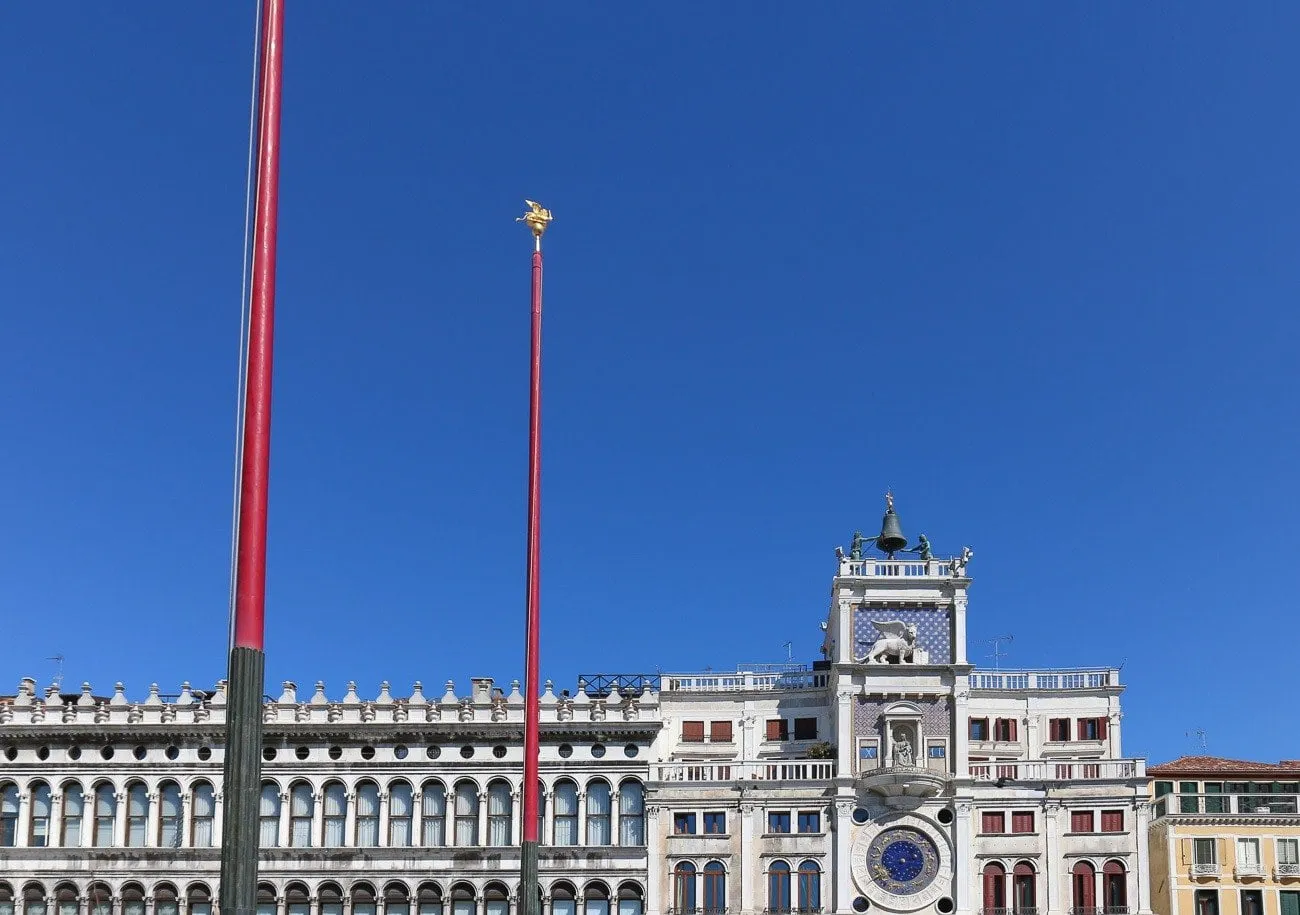 Lions on flag poles and the St. Mark's Clocktower in Venice, Italy.