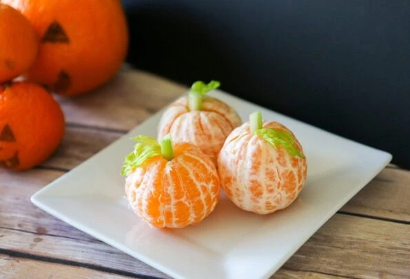 Little tangerine pumpkins with celery stems for a healthy Halloween snack recipe kids will love.