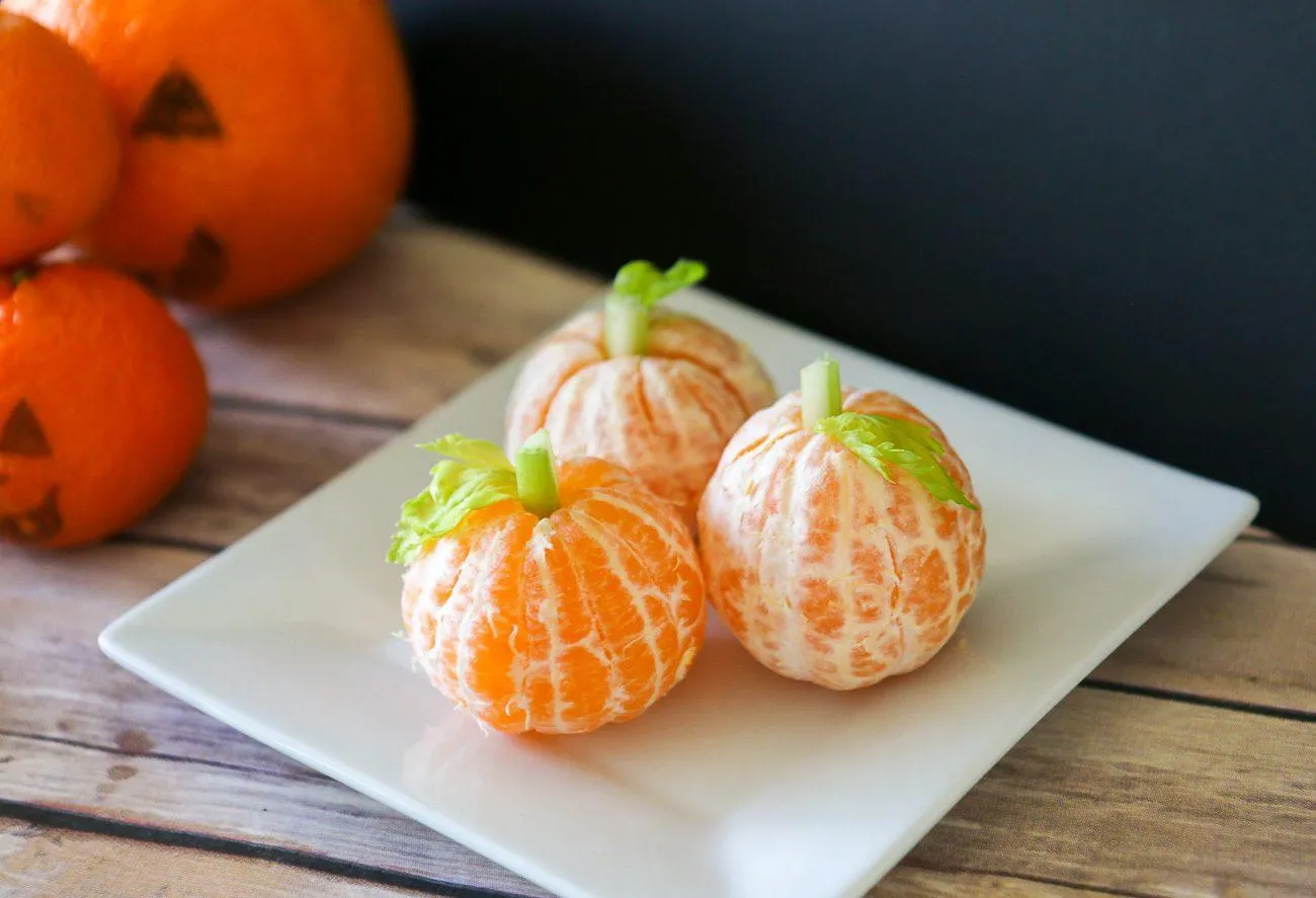 Little tangerine pumpkins with celery stems for a healthy Halloween snack recipe kids will love.