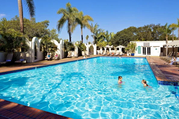 Two kids swim in the Bahia Resort Hotel's outdoor swimming pool on a sunny day.